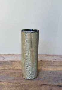 Cylindrical ceramic vase with textured surface on a wooden surface